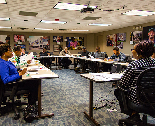 Image of group of people sitting around tables in a Goodwill classroom